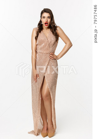 Christmas party and celebration concept. Full length of beautiful brunette woman looking surprised, wearing elegant dressed and gasping amazed at camera, white background 79757486
