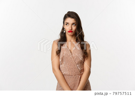 Celebration and party concept. Annoyed young woman losing temper, standing in glamour dress and looking away with bothered face, standing over white background Celebration and party concept. Annoyed young woman losing temper, standing in glamour dress and looking away with bothered face, standing over white background 79757511