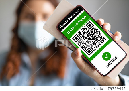 Young girl wearing a face mask holding a passport, ticket pass and smartphone with digital health passport app for travel during covid-19 pandemic. Young girl wearing a face mask holding a passport, ticket pass and smartphone with digital health passport app for travel during covid-19 pandemic. 79759445
