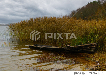 An old boat on the shore of the lake in the autumn on a cloudy day. 79762603