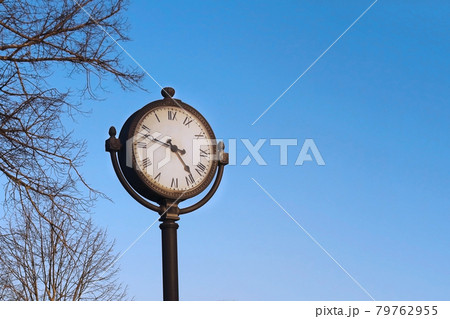 Round outdoor clock with roman numerals on spring blue sky background 79762955