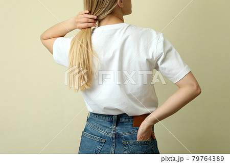 Young woman in blank t-shirt against beige background 79764389