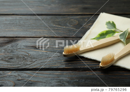 Napkin with eco friendly toothbrushes and twig on wooden background Napkin with eco friendly toothbrushes and twig on wooden background 79765296