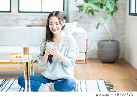 朝食を食べながらスマホを見る若い女性 朝食を食べながらスマホを見る若い女性 79767475