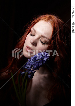 Portrait of girl with long red hair, good skin, with hyacinth on a black background 79767788