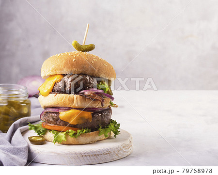 Home made burgers with two cutlets and melted cheese on a concrete gray background Home made burgers with two cutlets and melted cheese on a concrete gray background 79768978