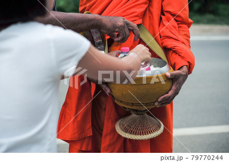Rear view of girl puts the food into the bowl of monk during making the merit Rear view of girl puts the food into the bowl of monk during making the merit 79770244