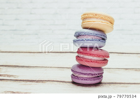 Multicolored macarons on a table and white wall background 79770534