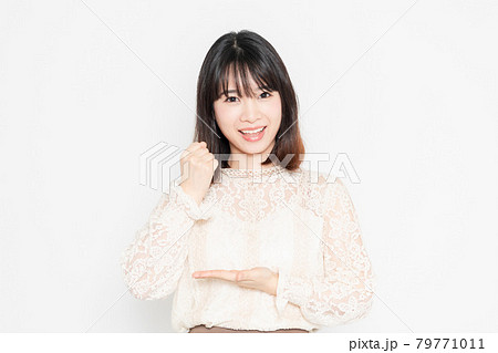 白背景の前に立って、納得のジェスチャーをする、レースのブラウスを着た若い女性 79771011