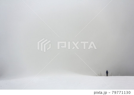 Far away lonely figure of a man standing outdoors in winter Far away lonely figure of a man standing outdoors in winter 79771130