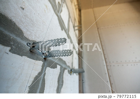 Unfinished brick wall in a room under construction prepared for drywall plates frame installation. 79772115