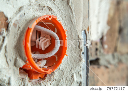 Socket orange boxes with wires in a wall. Cabling installation of electrical wires sticking out from electrical sockets hole on brick wall. Socket orange boxes with wires in a wall. Cabling installation of electrical wires sticking out from electrical sockets hole on brick wall. 79772117