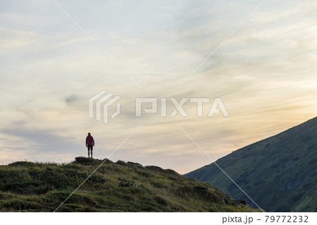 Dark silhouette of a hiker on a mountain at sunset standing on summit like a winner. 79772232