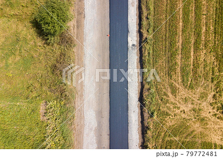 Aerial view of new road construction with newly layed black asphalt lane. 79772481