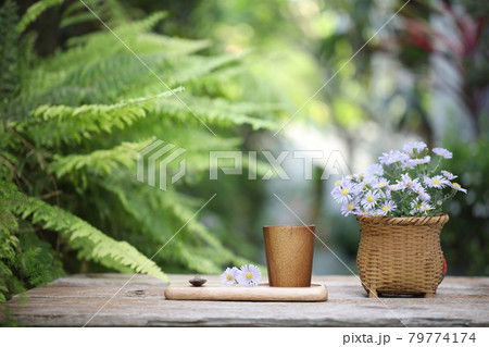 Wooden cup on wooden plate with purple aster flowers on wooden table and fern leaves  79774174