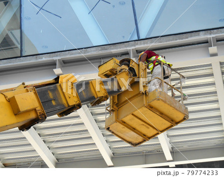 KUALA LUMPUR, MALAYSIA -MARCH 16, 2017: Construction workers standing in the sky lift bucket while working at high level in the construction site. The bucket movement control by the workers himself. KUALA LUMPUR, MALAYSIA -MARCH 16, 2017: Construction workers standing in the sky lift bucket while working at high level in the construction site. The bucket movement control by the workers himself. 79774233