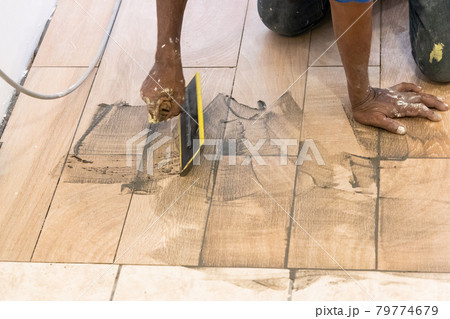 Worker applying grout onto newly laid ceramic tile. Motion blur intended. 79774679