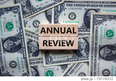 Annual review symbol. Concept words 'annual review' on wooden blocks on a beautiful background from dollar bills. Business and annual review concept, copy space. Annual review symbol. Concept words 'annual review' on wooden blocks on a beautiful background from dollar bills. Business and annual review concept, copy space. 79778352