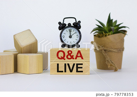 Q and A, questions and answers live symbol. Concept words 'Q and A live' on wooden blocks on a beautiful white background. Black alarm clock and house plant. Business and Q and A live concept. 79778353