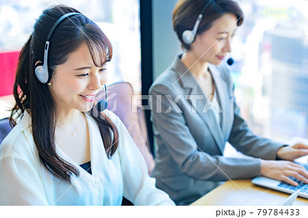 オフィスでヘッドセットをつけて対応する若い女性オペレーター オフィスでヘッドセットをつけて対応する若い女性オペレーター 79784433