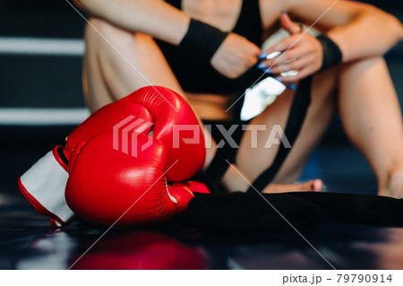 Close-up of red boxing gloves on the floor of a blue boxing ring Close-up of red boxing gloves on the floor of a blue boxing ring 79790914