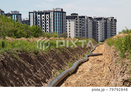 A large pipe lies in the trench. Water routing to the new house. house with water. residential complex A large pipe lies in the trench. Water routing to the new house. house with water. residential complex 79792848