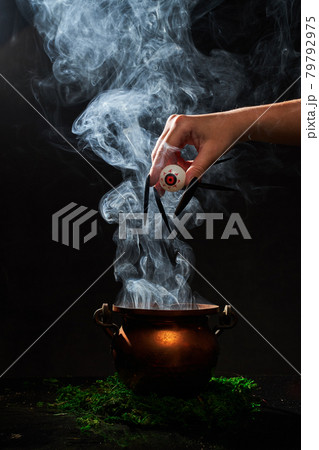The witch's hand put her eye in the smoking cauldron. 79792975