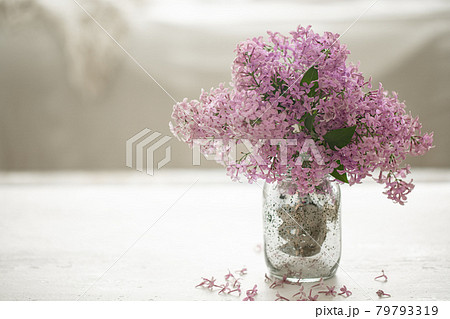 Bouquet of lilacs in a glass vase on a blurred background. Bouquet of lilacs in a glass vase on a blurred background. 79793319