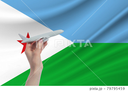 Airplane in hand with national flag of Djibouti. Travel to Djibouti 79795459