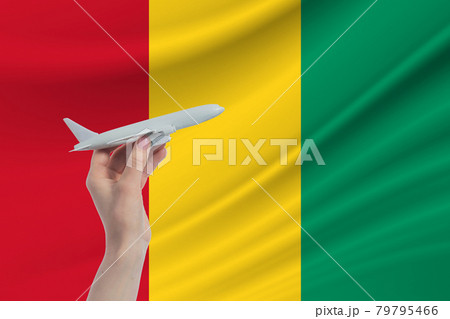 Airplane in hand with national flag of Guinea. Travel to Guinea Airplane in hand with national flag of Guinea. Travel to Guinea 79795466