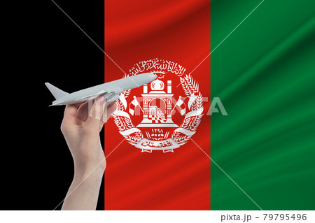 Airplane in hand with national flag of Afghanistan. Travel to Afghanistan 79795496