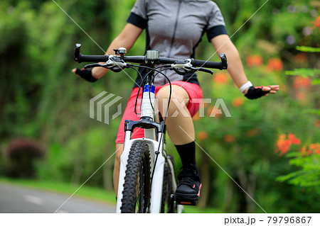Woman no handed cycling on tropical park trail in summer 79796867