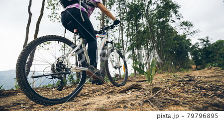 Woman cycling on mountain top forest trail Woman cycling on mountain top forest trail 79796895