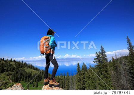 Successful woman backpacker hiking on forest mountain peak 79797345