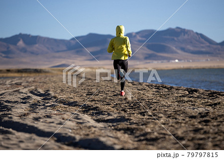 Woman trail runner cross country running on winter high altitude lakeside 79797815