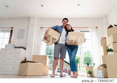 Happy young couple Carrying cardboard boxes and standing in the front door of a new house at moving day. Concept of relocation, rental, and homeowner moving at home. 79800247