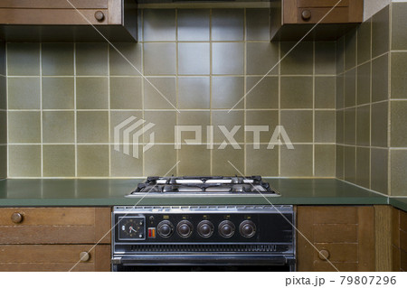 Interior of a old retro vintage kitchen with antique oven with brown wooden cabinets, green old school stylish tiles,needs renovation 79807296