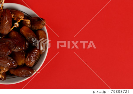Cropped image of a plate full of fresh mediterranean delicious and tasty dates. Red background, copy space 79808722