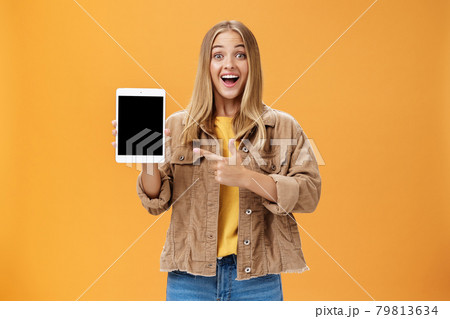 Woman showing friends new digital tablet first purchace of autumn. Charismatic and enthusiastic excited caucasian female with tanned skin and fair hair in corduroy jacket pointing at gadget screen 79813634