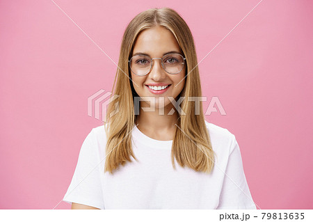Creative and smart good-looking friendly female with tanned skin and little pimples wearing glasses and white t-shirt smiling broadly with perfect teeth standing plesant over pink wall 79813635