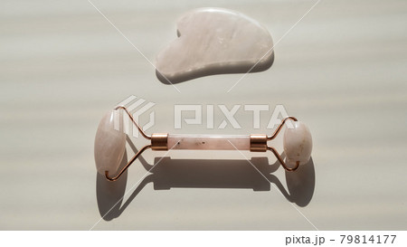 Pink guache scraper and roller on a white table. Equipment for self-massage and skin care for the face and neck 79814177