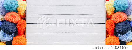 Colorful yarn balls in wooden box on white wood boards background. 79821655