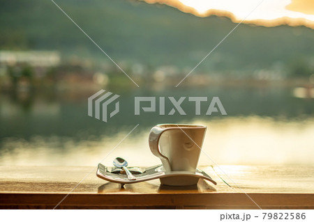 hot coffee cup on wood table against lake view background at coffee shop in the morning sunrise, Ban Rak Thai village, Mae Hong Son province, Thailand 79822586