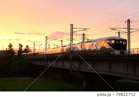 夕焼けの朱色に車体を染めて夕陽に向けて走る「TRAIN SUITE 四季島」（回送列車，後追い） 79822752