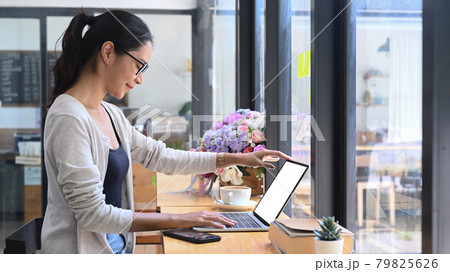 Side view casual female working with laptop at coffee shop. Side view casual female working with laptop at coffee shop. 79825626