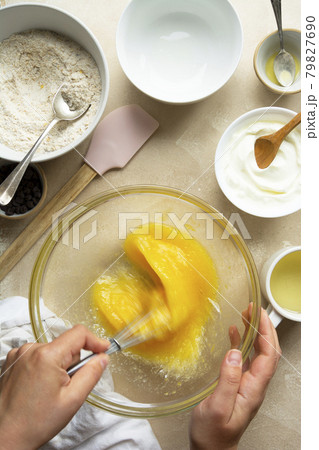 Female hands cooking a cake in glass bowl, top view. Mixing sugar and eggs in glass bowl. Step by step recipe. Female hands cooking a cake in glass bowl, top view. Mixing sugar and eggs in glass bowl. Step by step recipe. 79827690