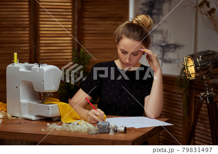 Beautiful young seamstress working on sewing machine Beautiful young seamstress working on sewing machine 79831497
