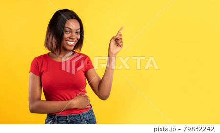 African American Woman Pointing Finger Aside Over Yellow Background 79832242