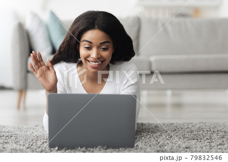 Online chat. Smiling african american lady with laptop making video call, waving hand to webcam, resting at home 79832546