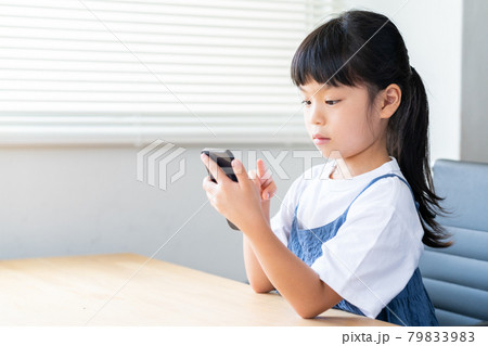 部屋でスマホを使う小学生の女の子 部屋でスマホを使う小学生の女の子 79833983